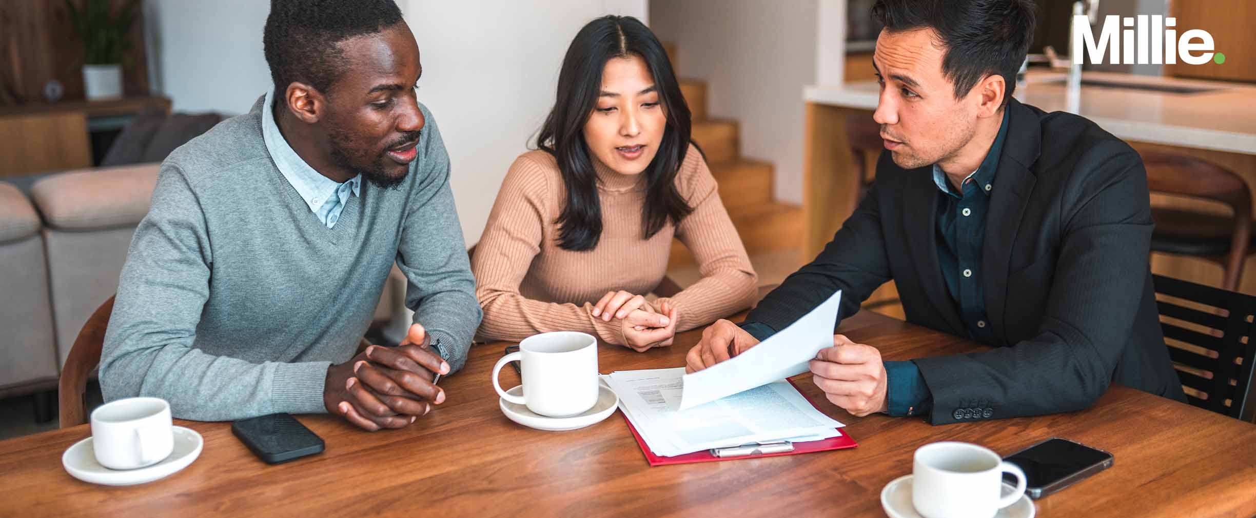 Una pareja sentada en una mesa discutiendo un acuerdo prenupcial con un abogado.