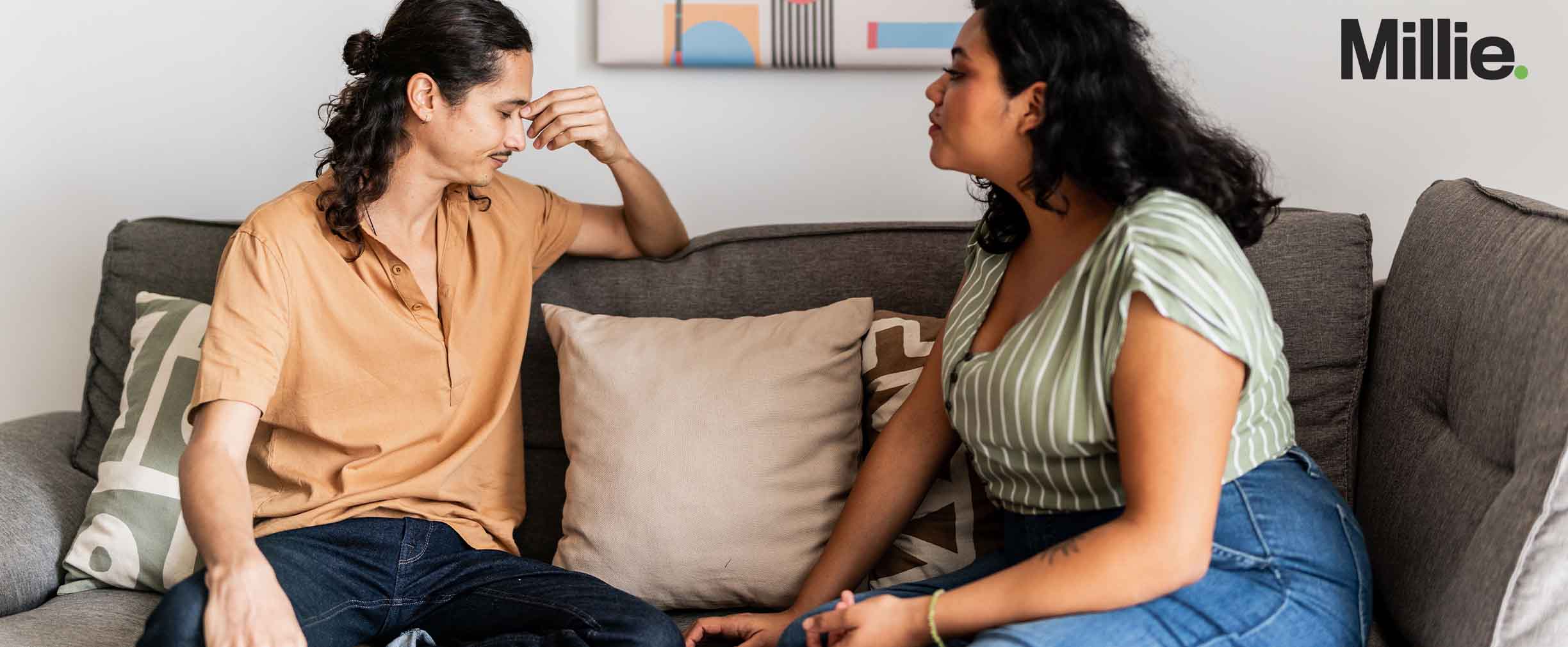 Una pareja frustrada sentada en un sofá discutiendo sobre deudas.