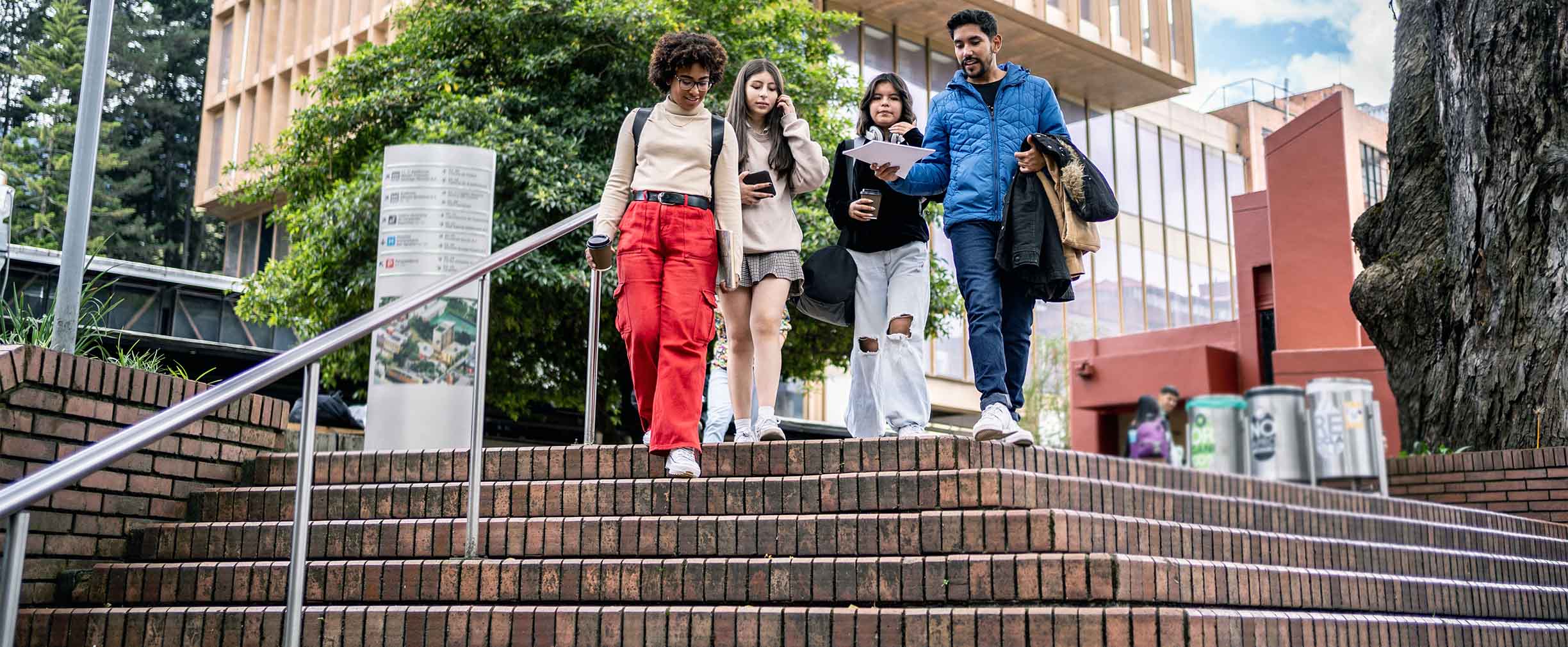 Cuatro jóvenes estudiantes pasean por un campus universitario y conversan