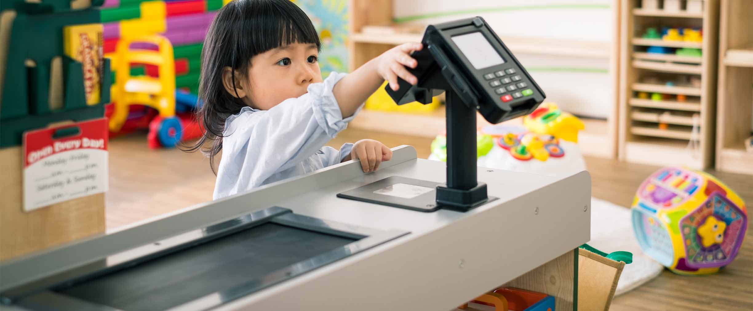 Una niña de preescolar juega con el escáner de tarjetas de crédito en la caja de un supermercado