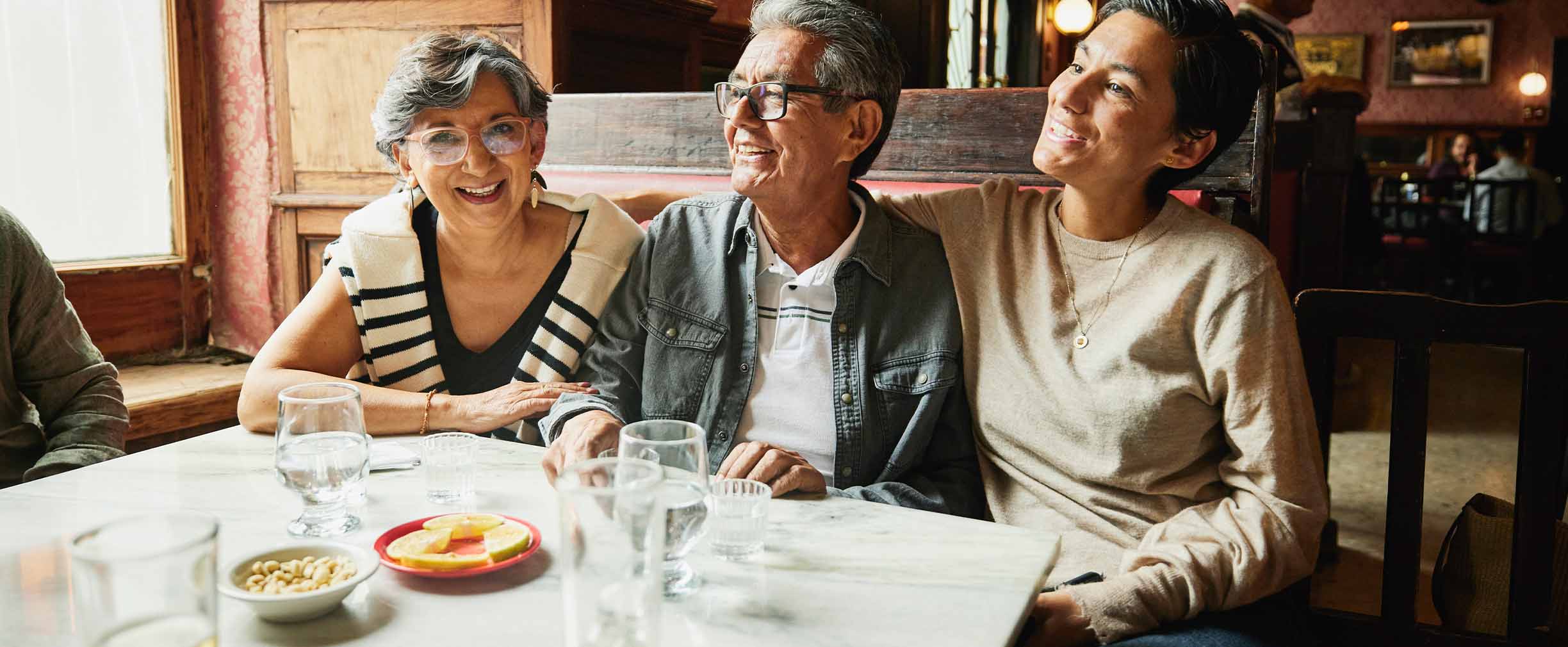 Una mujer sentada en un restaurante con sus padres que sonríen